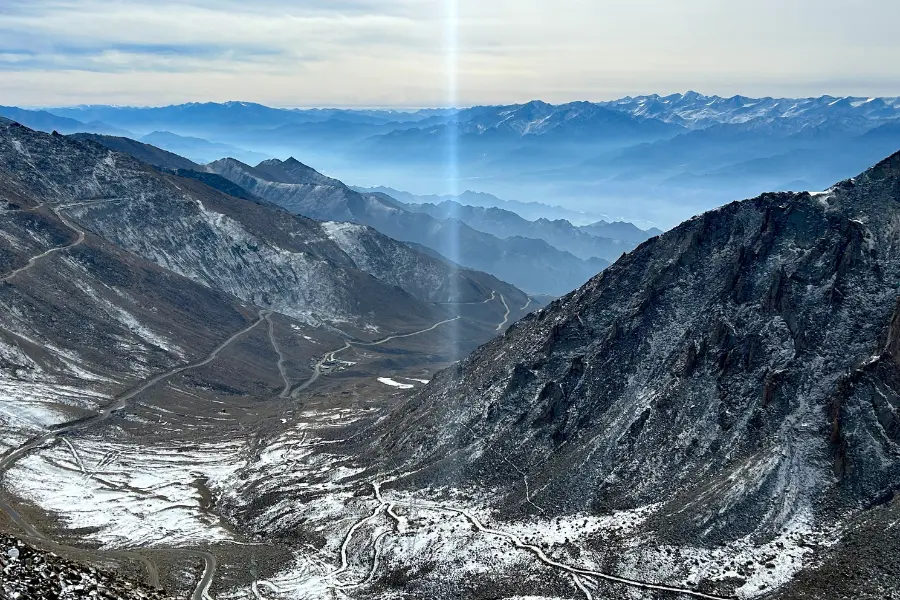 View of snow-covered mountain ranges with trails and misty blue horizons in the Himalayas.