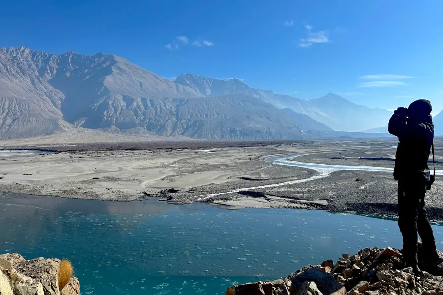 Traveller overlooking a river valley with mountains in Ladakh